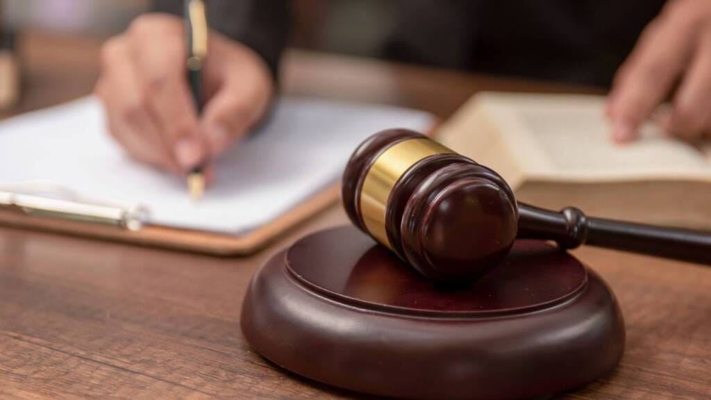 Gavel resting beside a lawyer's hands writing legal documents, symbolizing EU Cyber Resilience Act compliance preparation.